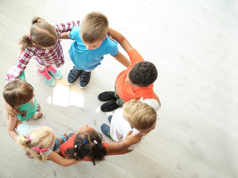 A group of children standing in a circle, seen from above
